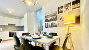 A modern dining area with a white table set for four, black chairs, a vase with dried flowers, and a floor lamp. - Luxury 2BR 1BA Near Fashion District by Oneluxstay (Antwerp)