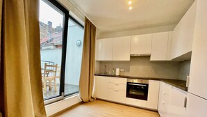 A modern kitchen with white cabinets, a built-in oven, and a large window with curtains. - Luxury 2BR 1BA Near Fashion District by Oneluxstay (Antwerp)