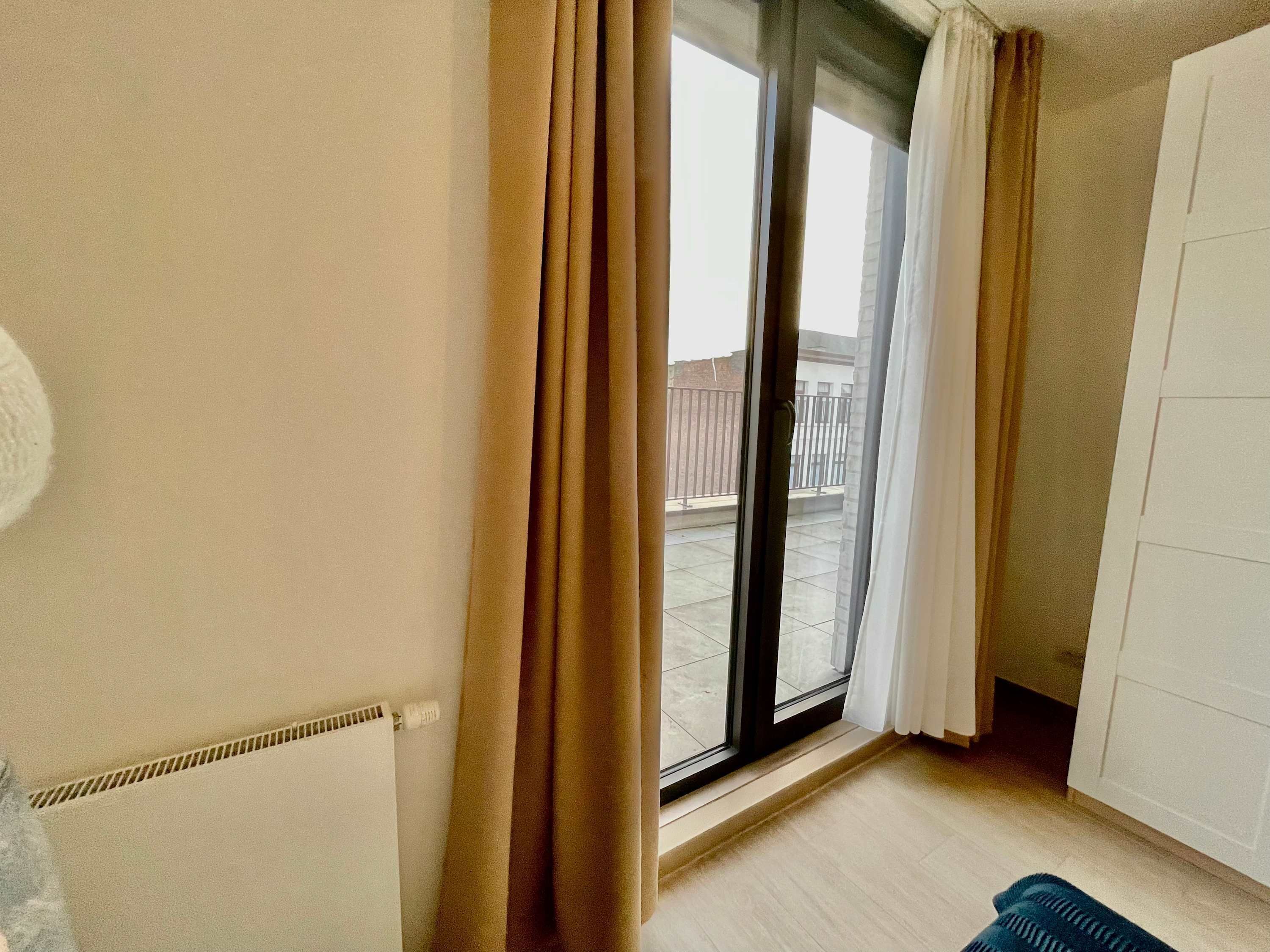 A room with a large sliding glass door leading to an outdoor balcony.