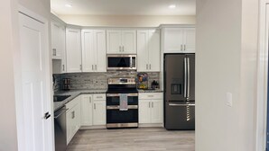 Una cocina moderna con gabinetes blancos, electrodomésticos de acero inoxidable y encimera de granito.