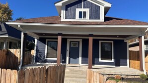Una casa residencial con un porche cubierto, una puerta principal y un ventanal pequeño.