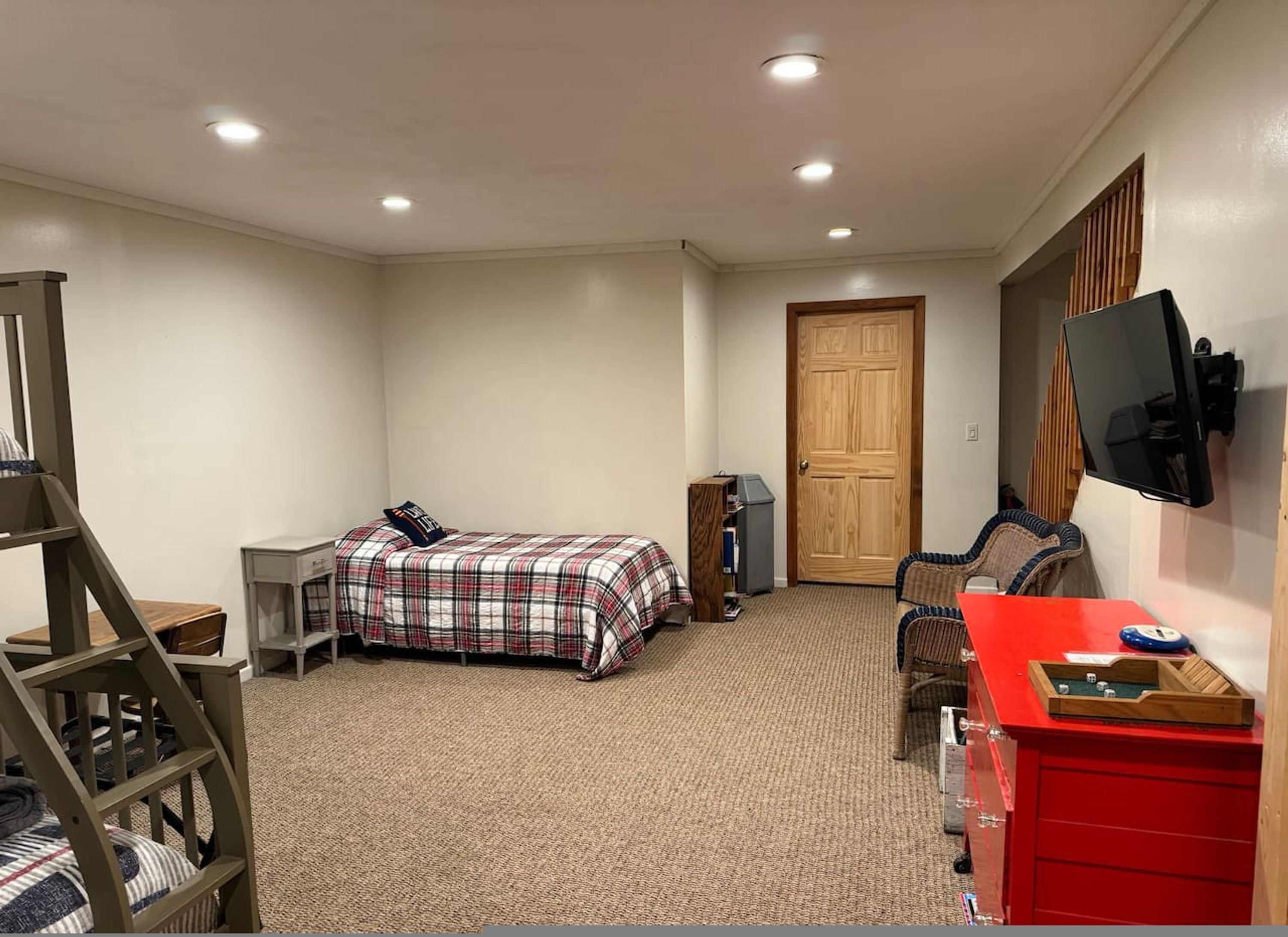Een slaapkamer met een bed, een bureau, een stoel, een televisie en een dressoir.