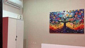 Une chambre à coucher avec un lit, une table de chevet, une armoire et un tableau coloré au mur.
