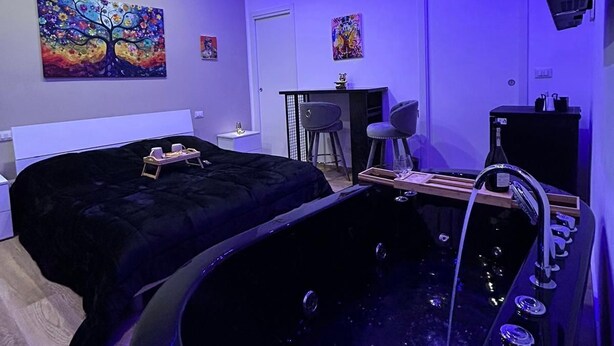 Une chambre à coucher moderne avec une grande baignoire noire, un lit et un espace bureau.