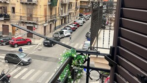 Vista de la calle desde un balcón, con coches aparcados y edificios al fondo.