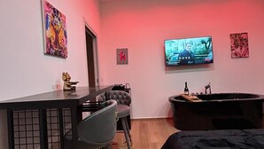 Une chambre moderne dotée d’un coin bar, d’un grand téléviseur et d’une baignoire.