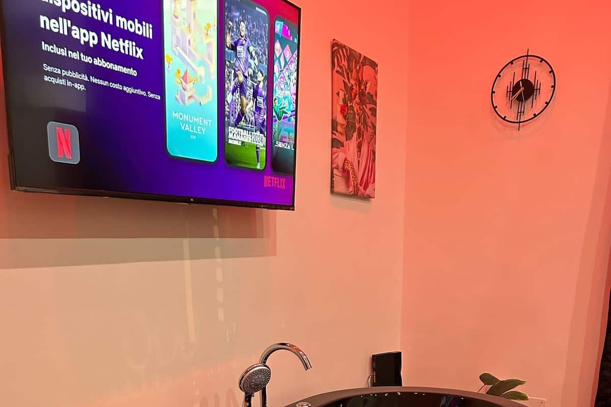A modern bathroom with a freestanding bathtub, candles, and a Netflix advertisement on the wall.