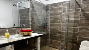Ein modernes Badezimmer mit Duschkabine aus Glas, Marmorplatte und Toilette.
