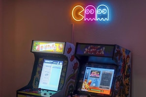 Two arcade machines with screens displaying game interfaces, one with a Pac-Man theme and the other with a Street Fighter theme.