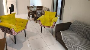 A living room with two yellow armchairs, a brown sofa, a dining table with chairs, and a painting on the wall. - Apartment in Peroba/Maragogi (Barra Grande)