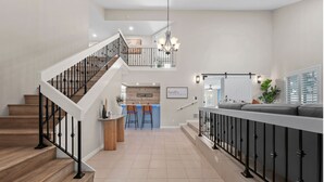 A spacious living area with a staircase, a kitchen area, and a seating area with a sofa and a dining table. - The Fairway Retreat at Vista del Verde (San Diego)