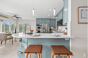 A modern kitchen with a central island, blue cabinets, stainless steel appliances, and pendant lighting.