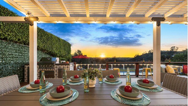 An outdoor dining area with a view of the sunset, a pool, and a pergola. - The Fairway Retreat at Vista del Verde (San Diego)