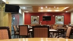 A conference room with a large table in the foreground, multiple chairs, a flat-screen TV mounted on the wall, and framed artwork on the walls. - HOTEL LA MINA PARRAL (Hidalgo del Parral)