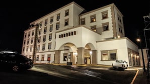 A multi-story hotel with a white facade, multiple windows, and a central entrance with arches. - HOTEL LA MINA PARRAL (Hidalgo del Parral)