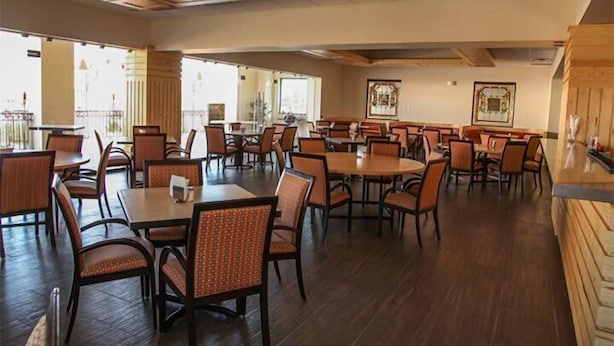 A spacious indoor dining area with multiple tables and chairs, wooden flooring, and large windows allowing natural light. - HOTEL LA MINA PARRAL (Hidalgo del Parral)