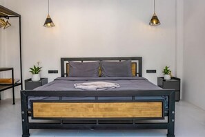 Une chambre à coucher moderne avec un lit, des tables de chevet et des lampes suspendues.