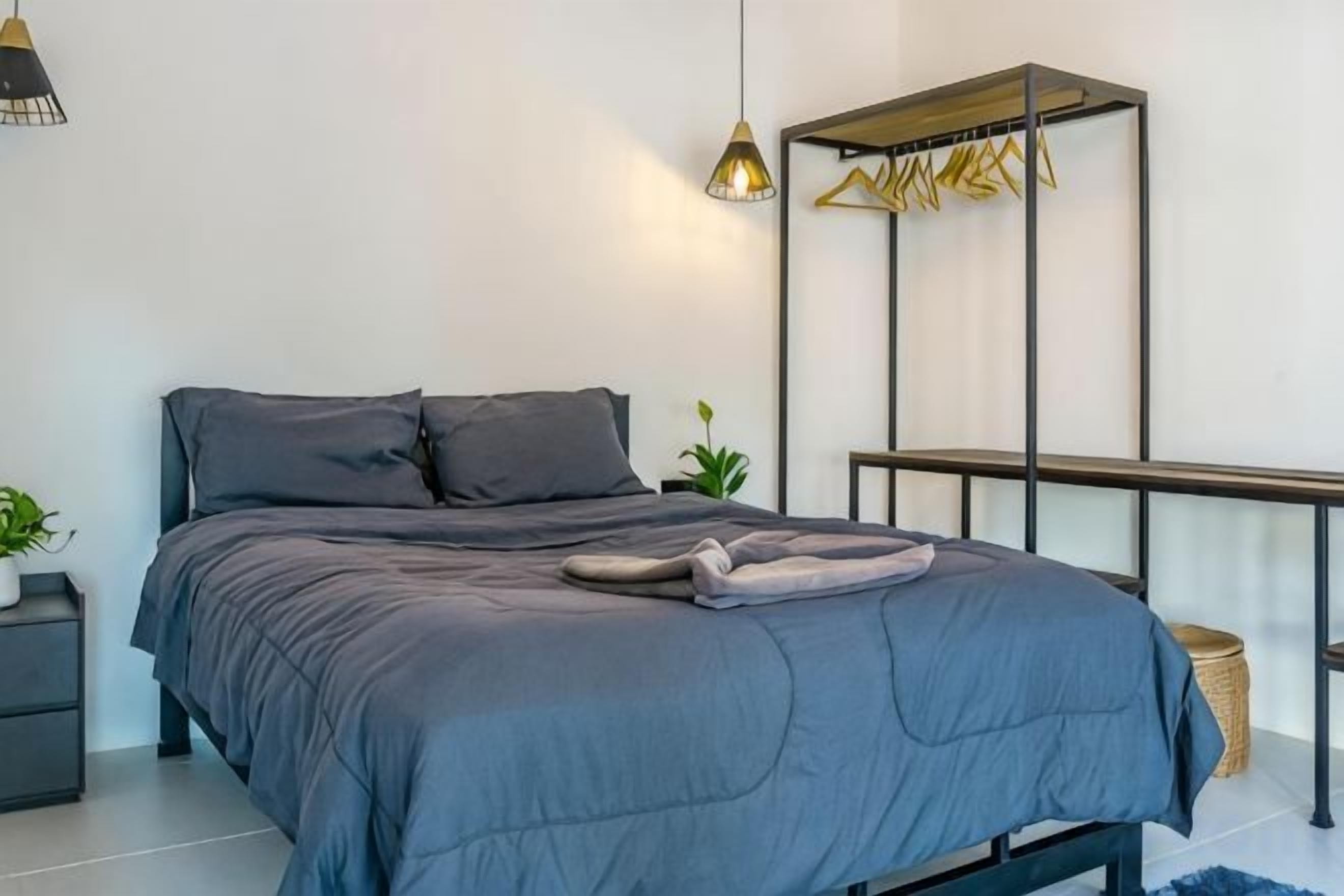 A modern bedroom with a bed, bedside tables, and a hanging light fixture.