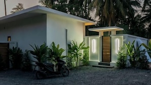 A modern house with a driveway, a motorcycle, and a well-maintained garden. - Ozzy Villa Phangan (Koh Phangan)