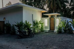 Une maison moderne avec une allée, une moto et un jardin bien entretenu.
