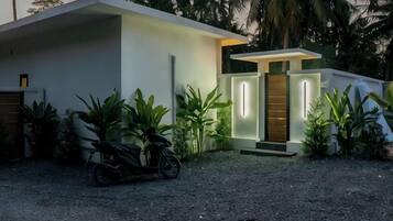 A modern house with a driveway, a motorcycle, and a well-maintained garden.