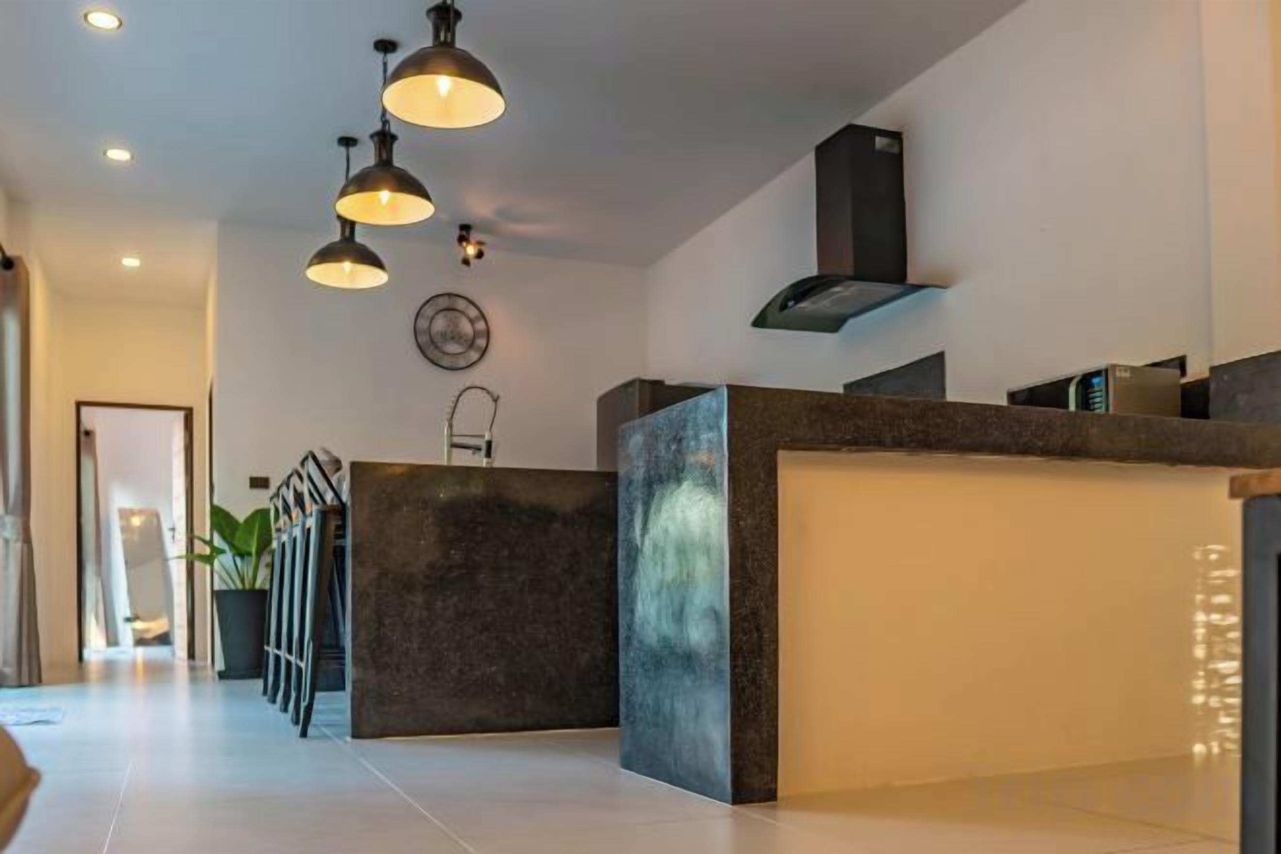 A modern interior with a reception desk, pendant lighting, and a staircase.