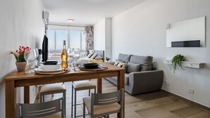 Una sala de estar moderna con comedor, sofá gris y vistas de la ciudad.