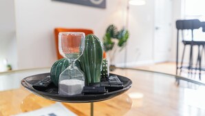 Ein modernes Interieur mit einem Glastisch, auf dem eine Sanduhr, ein Kaktus und eine Fernbedienung zu sehen sind.
