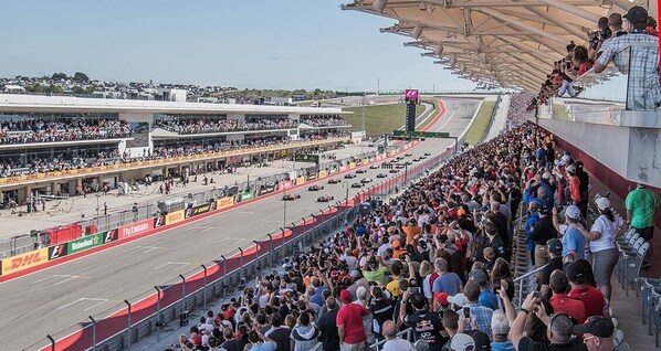 A crowded race track with spectators and a grandstand.