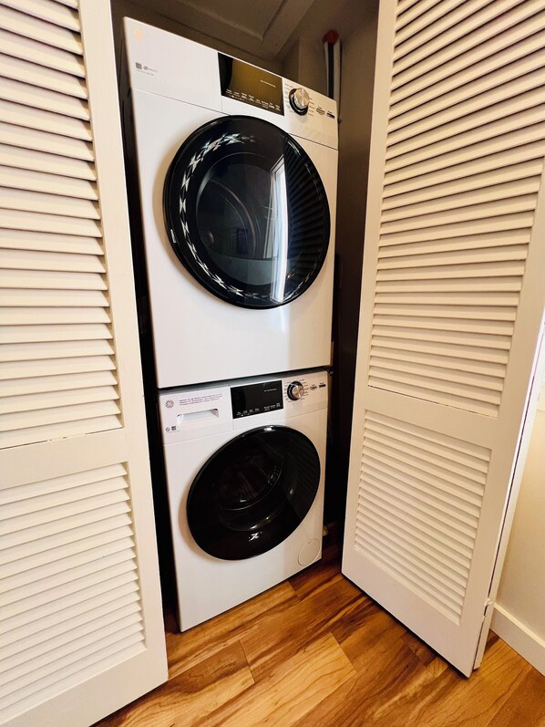 Une petite buanderie à deux portes, dotée d’un lave-linge et d’un sèche-linge intégrés.
