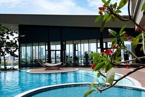 An indoor swimming pool with a view of the city skyline, surrounded by large windows and a few lounge chairs. - Kenwingston Skyloft Apartment Doorsteps to Brt Subang USJ (Subang Jaya)