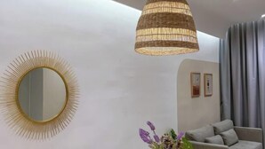 A modern living room with a round mirror, a hanging light fixture, and a grey sofa. - Kenwingston Skyloft Apartment Doorsteps to Brt Subang USJ (Subang Jaya)