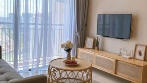 A living room with a sofa, a round coffee table, a TV mounted on the wall, and a wooden console table with decorative items. - Kenwingston Skyloft Apartment Doorsteps to Brt Subang USJ (Subang Jaya)