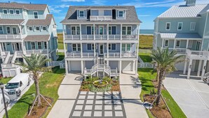A multi-story beachfront property with a central staircase, a driveway, and a small garden area. - Featured in American Dream Home !  Stunning Oceanfront Views for Days !! (Galveston)