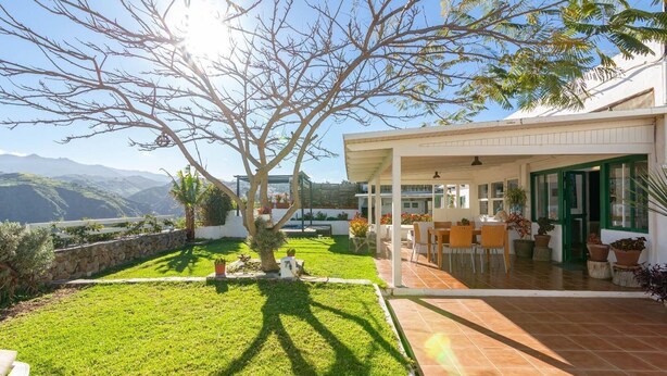 Uma casa moderna com um pátio, gramado e vista para as montanhas.