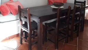 A dining area with a dark wooden table, six chairs, and red cushions.