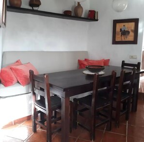 A dining area with a dark wooden table, six chairs, and red cushions.