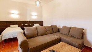 A room with a bed, a sofa, a coffee table, and a hanging light fixture.