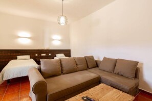A room with a bed, a sofa, a coffee table, and a hanging light fixture.