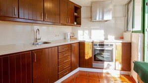 A kitchen with wooden cabinets, a stainless steel sink, a built-in oven, and a window with a view.