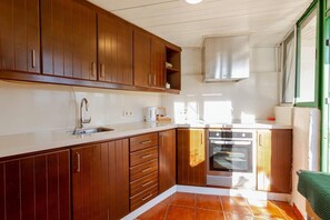 A kitchen with wooden cabinets, a stainless steel sink, a built-in oven, and a window with a view.