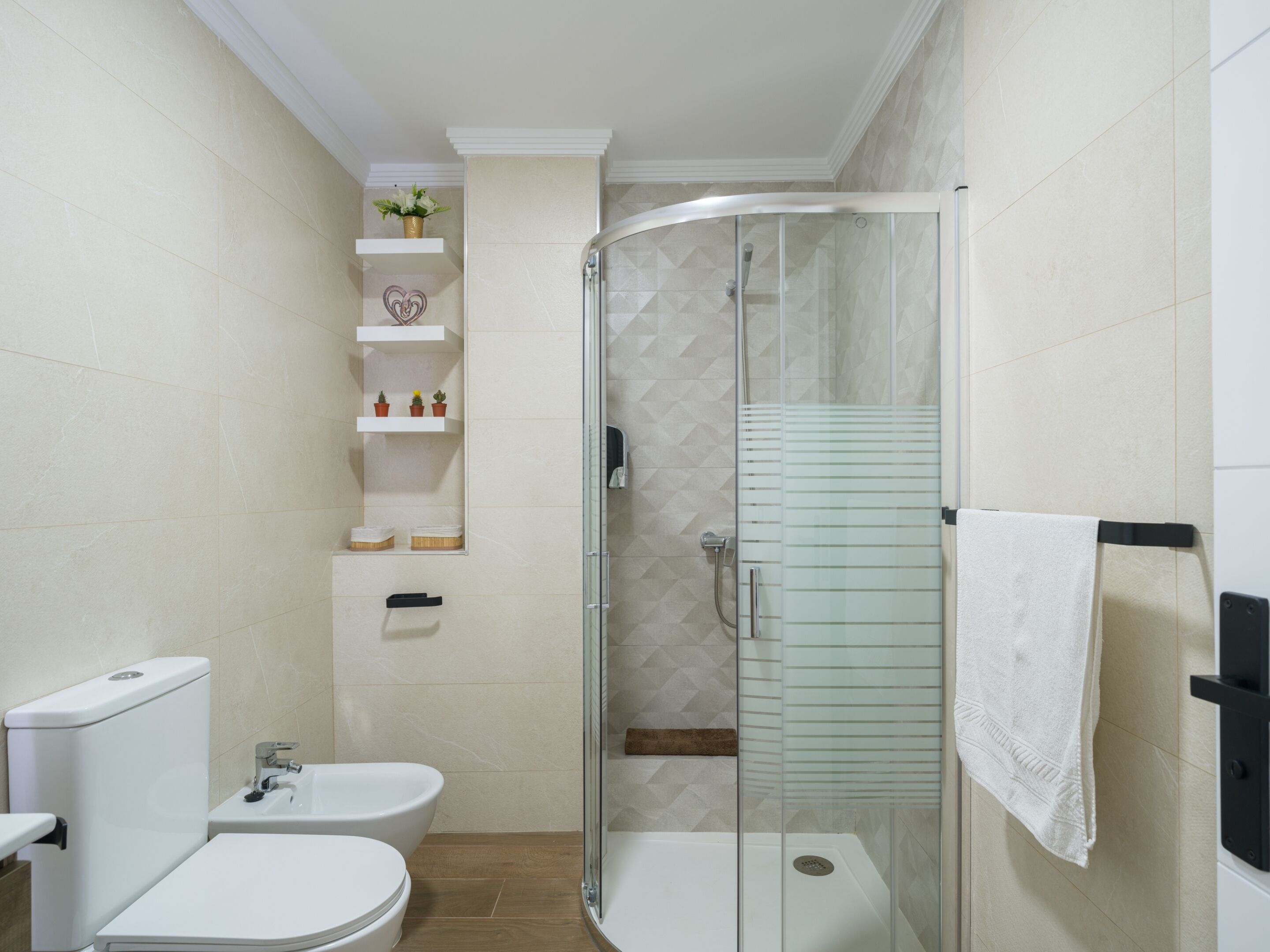A modern bathroom with a glass shower enclosure, a toilet, a bidet, and a sink.