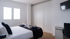 Ett hotellrum med en säng, ett skrivbord, en stol, en tv och en garderob.