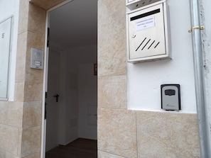 An interior hallway with a door, a fire alarm, and a utility box with labels.