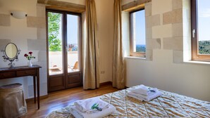 A bedroom with a bed, a desk, a mirror, and a view of the outdoors. - Villa Erontas Mini Pool and Heated Jacuzzi (Apokoronas)