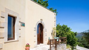 A building with a stone staircase leading to a wooden door, a small table with chairs, and a potted plant. - Villa Erontas Mini Pool and Heated Jacuzzi (Apokoronas)