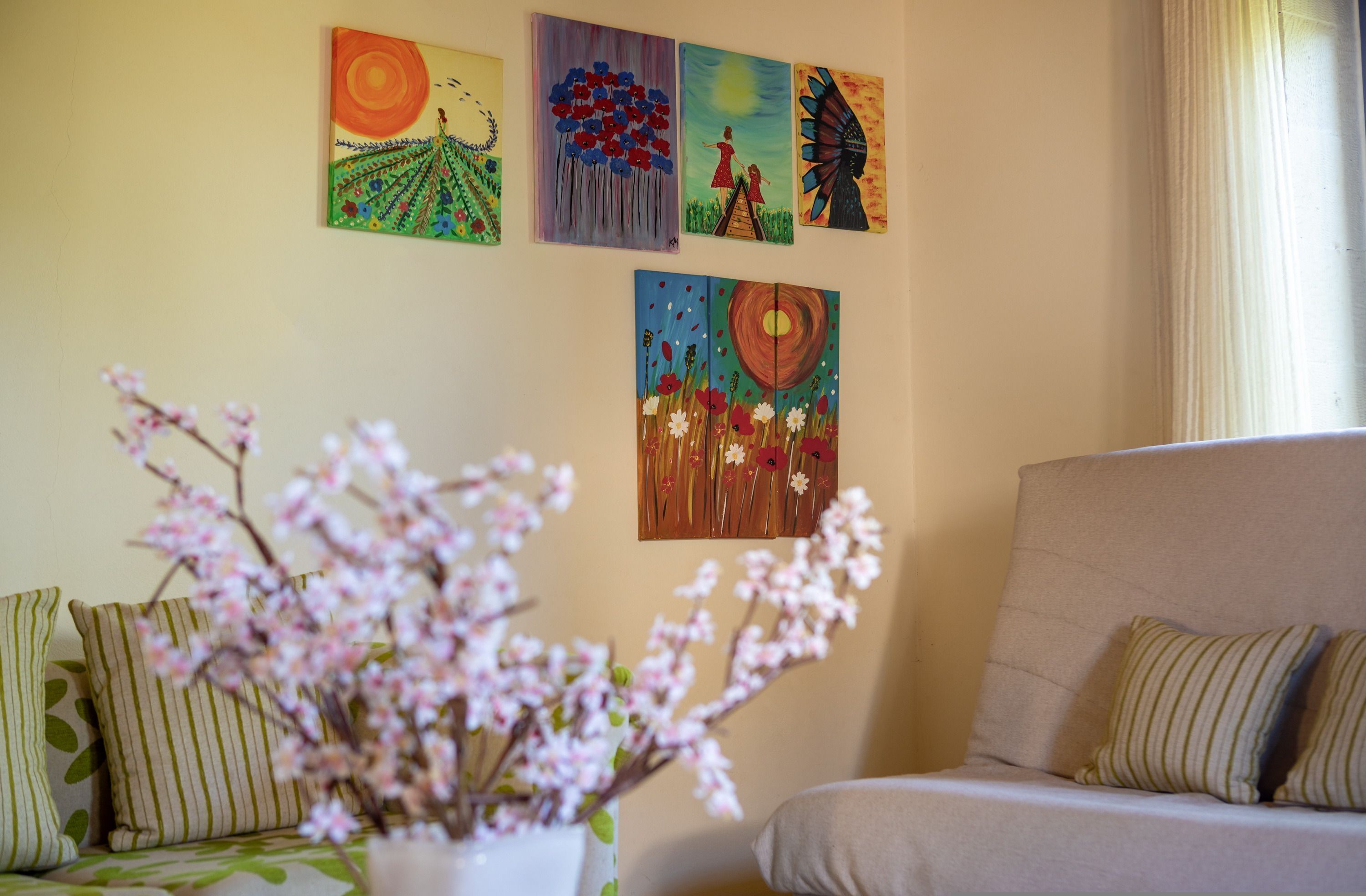 Ein Wohnzimmer mit einer Couch, einem Couchtisch mit Blumenvase und vier Bildern an der Wand.