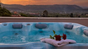 Un jacuzzi con vista al atardecer, una toalla y dos rosas.