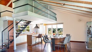 Une cuisine moderne dotée d’un îlot central, d’un coin repas avec une table ronde et des chaises, et d’un escalier menant à un niveau supérieur.