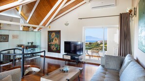 Un salon moderne avec un plafond en bois, un canapé, une table basse et un téléviseur.